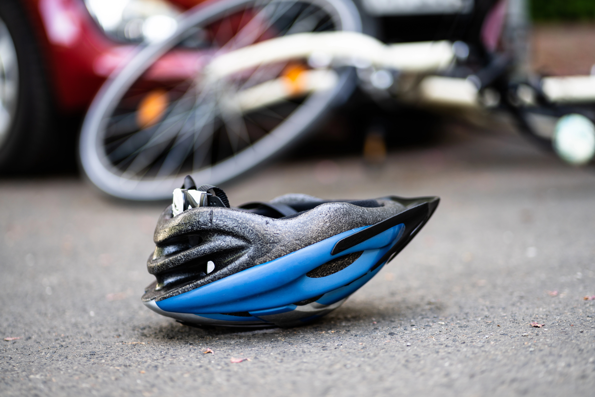 Cyclist helmet on pavement after crash with bicycle in background, illustrating Ontario bicycle accident benefits changes in 2026 and injury claims.
