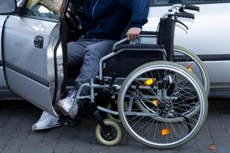 Wheelchair beside a vehicle, representing future care costs, long-term rehabilitation, and ongoing support after a serious personal injury.