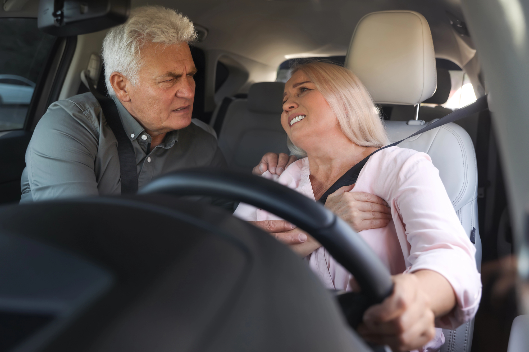 Older woman experiencing pain after a car accident while a passenger comforts her, illustrating how pre-existing medical conditions can affect a personal injury claim in Ontario.