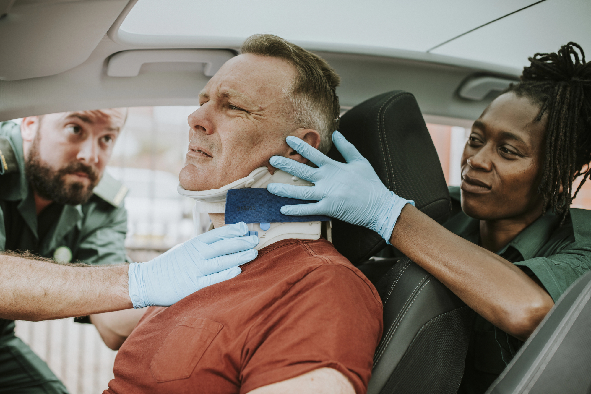 Paramedics stabilizing a driver with a neck brace after a motor vehicle collision, illustrating a whiplash injury claim and compensation for neck injuries in Ontario.